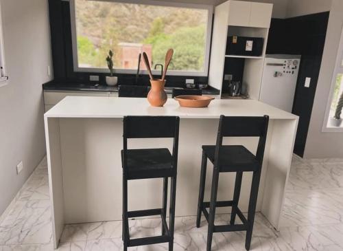 a kitchen with two stools and a counter with a window at Inti Belén in Belén