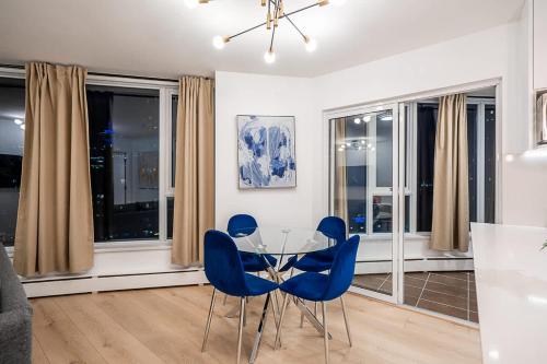a dining room with a glass table and blue chairs at Gorgeous Downtown Unit with City Views in Vancouver