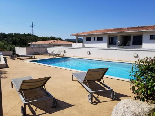 une piscine avec deux chaises à côté d'une maison dans l'établissement A SUARA- CORSE- APPARTEMENT 2 chambres 5 à 7 pers, jardin et piscine, à Porto-Vecchio