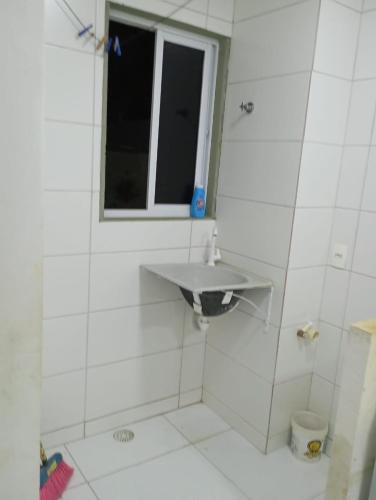 a white bathroom with a sink and a window at Condomínio Engenho Planalto in Maricota