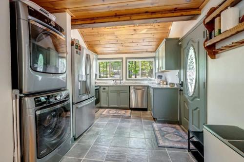 a kitchen with green cabinets and a washer and dryer at Chic Cabin with 3 Kings Privacy & Pool Access in Hedgesville