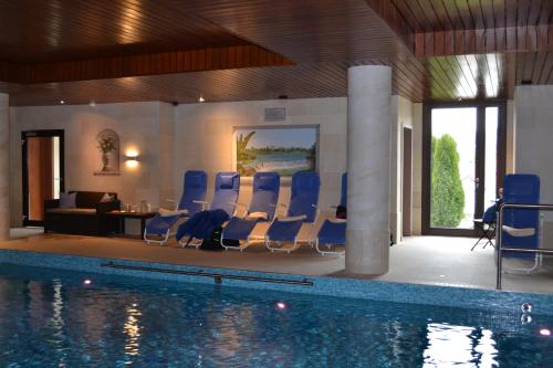 a swimming pool with blue chairs in a room at Landhotel Spessartruh in Frammersbach