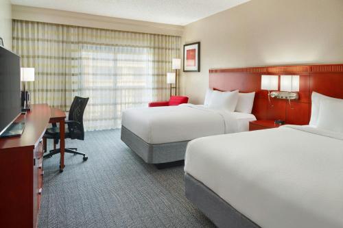 a hotel room with two beds and a desk at Courtyard by Marriott Baton Rouge Acadian Centre/LSU Area in Baton Rouge