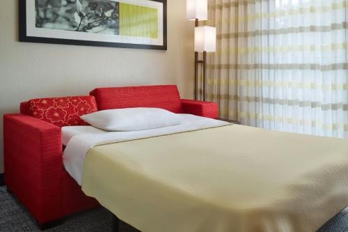 a hotel room with a bed and a red chair at Courtyard by Marriott Baton Rouge Acadian Centre/LSU Area in Baton Rouge