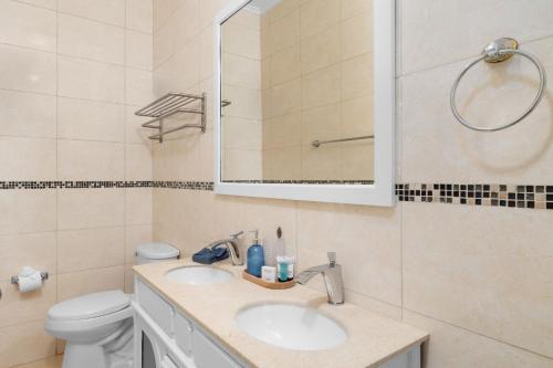 a bathroom with a sink and a toilet and a mirror at Aruba Breeze C4 in Palm-Eagle Beach