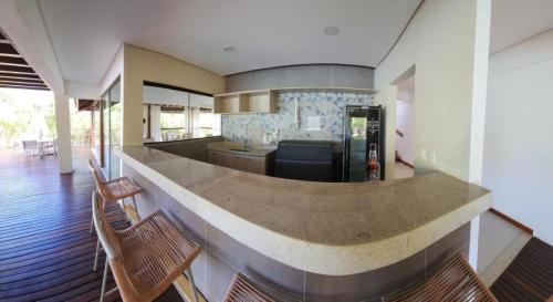 a kitchen with a counter with chairs and a refrigerator at Casa em Praia do Forte Refúgio Luxo e Natureza in Praia do Forte