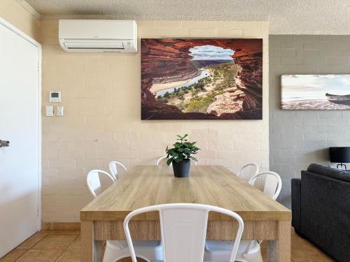 ein Esszimmer mit einem Holztisch und weißen Stühlen in der Unterkunft Riverview Holiday Apartment 60 - Kalbarri WA in Kalbarri