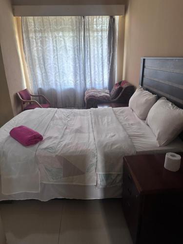 a bedroom with a large white bed and a window at Salvador Kruger in Vereeniging