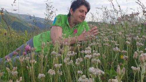 a woman sitting in a field of flowers at Котеджі Карпати Fest in Mizhhirʼʼya