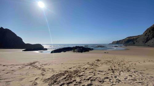 a beach with footprints in the sand and the ocean at Vale das Estrelas in São Teotónio