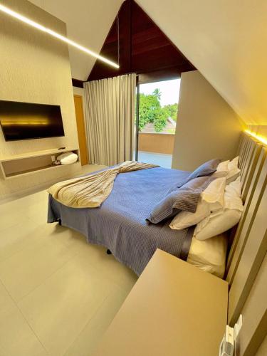 a bedroom with a bed and a large window at Bangalô com 3 suítes no Eco Resort na Praia dos Carneiros in Tamandaré