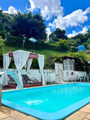a swimming pool with a water fountain at Pousada e Chalés Arco-Íris in Lima Duarte