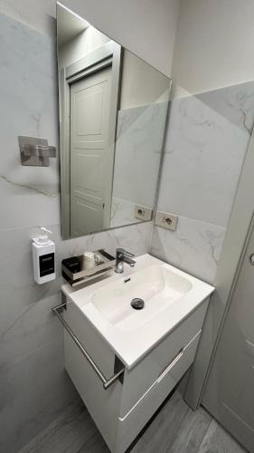 a white bathroom with a sink and a mirror at Baratà Apartments 1 in Savigliano