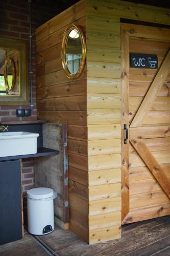a bathroom with a wooden wall with a door at Kampeerbeleving Dijksehoeve in Nistelrode
