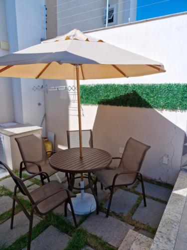 a wooden table with chairs and an umbrella at Ivana Imoveis - Casa com Piscina na Praia do Morro á 2 minutos da praia in Guarapari
