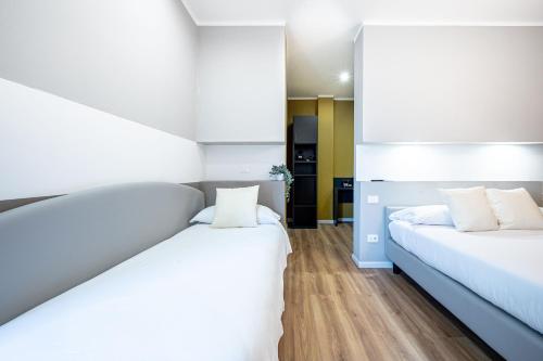 two beds in a room with white walls and wooden floors at - NumberZ - Rooms Apartments and Suites with Wi-Fi and AC in Borgo Isonzo
