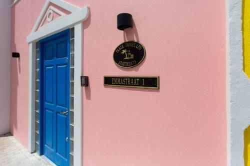 a pink building with a blue door and a sign at Dutch Caribbean Residence E in Madiki
