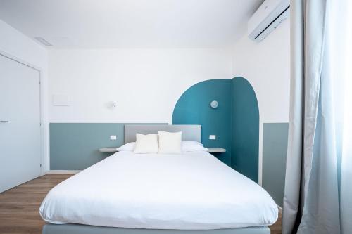 a bedroom with a white bed and a blue headboard at - NumberZ - Rooms Apartments and Suites with Wi-Fi and AC in Borgo Isonzo