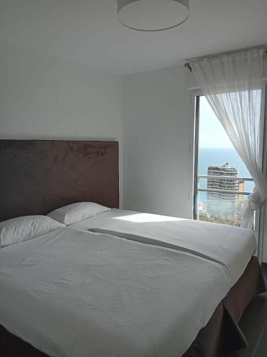 une chambre avec un grand lit avec une fenêtre dans l'établissement Luxury Apartment MonacoView, à Beausoleil