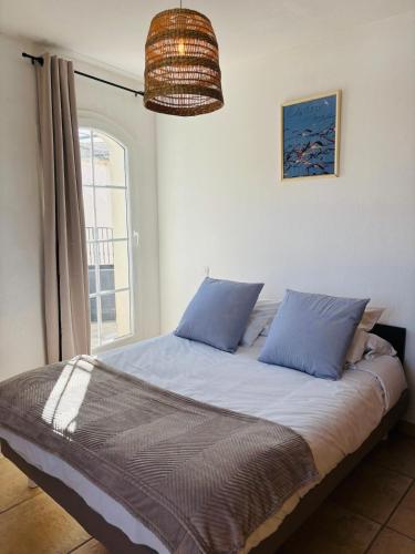 une chambre avec un lit avec des oreillers bleus et une fenêtre dans l'établissement Marina Le Paradis sur l'eau, à Aigues-Mortes