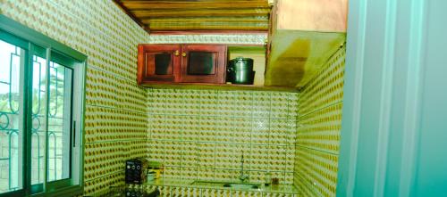 a kitchen with a yellow tiled wall at Maison Théodosius Plage avec Parking Intérieur in Kribi
