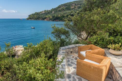 a pair of wicker chairs sitting on a stone wall near the water at Lithalona Villas & Houses in Marathias