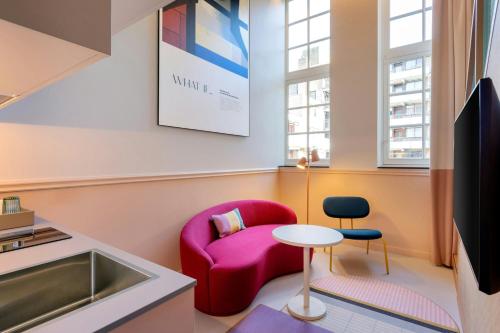 a living room with a red chair and a table at The Rebyl, Nijmegen, a Tribute Portfolio Hotel in Nijmegen