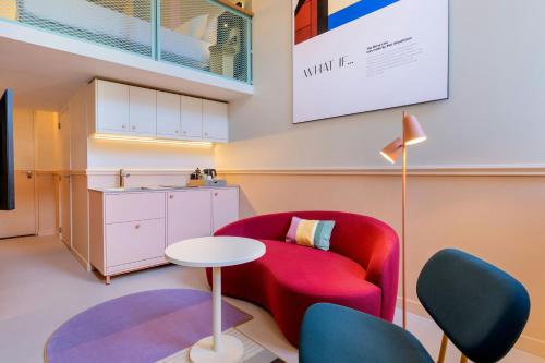 a living room with a red chair and a table at The Rebyl, Nijmegen, a Tribute Portfolio Hotel in Nijmegen