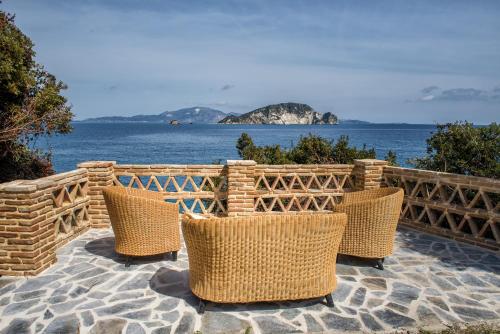 a group of chairs sitting on a patio overlooking the ocean at Lithalona Villas & Houses in Marathias