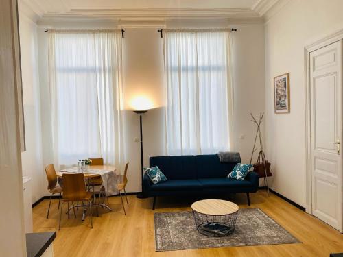 a living room with a blue couch and a table at Studio calme et lumineux à Uccle in Brussels
