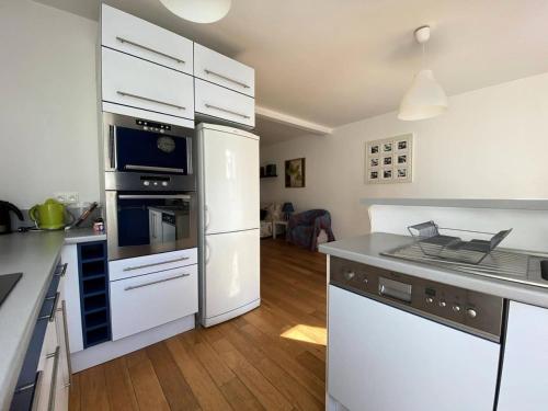 une cuisine avec des appareils électroménagers blancs et du parquet dans l'établissement Résidence 6 Rue A.c. - Appartement entièrement remis à neuf au cœur du Val-André. MAE-6544, à Pléneuf-Val-André