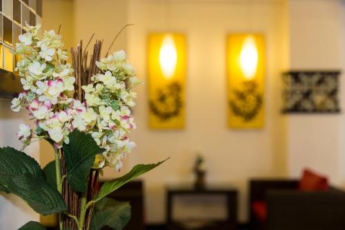a vase filled with white flowers in a room at Star House Patong in Patong Beach