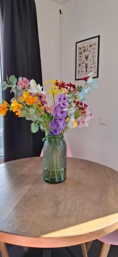 a vase of flowers sitting on a wooden table at De Strandloper Vakantiehuisje aan het strand - Ferienwohnung am Meer in Baarland