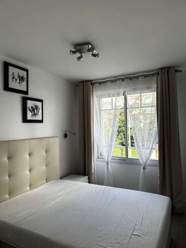une chambre avec un lit blanc et une fenêtre dans l'établissement Résidence Dignan - Arcachon - T3 centre-ville MAE-9464, à Arcachon