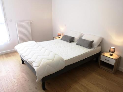 - un grand lit blanc dans une chambre avec 2 tables dans l'établissement Résidence Villa Marine - Appartement neuf T3 au centre-ville d'Arcachon MAE-9484, à Arcachon