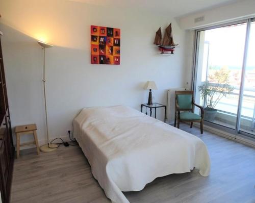 une chambre avec un grand lit blanc et une chaise dans l'établissement Résidence Les Flots - T3 6 personnes à Arcachon, vue sur le Bassin MAE-9554, à Arcachon