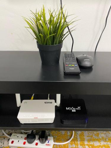 a black desk with a plant and a remote control at Mesahill Studio King With Massage Chair Above Shopping Mall, Cinema & Bowling, 5 Minutes to USIM, Nilai - 24H Self and Easy Check In in Nilai