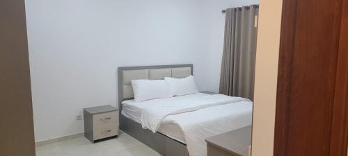 a bed with white sheets and pillows in a bedroom at مراسيم للشقق الفندقية in Amman