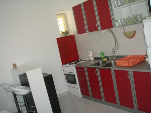 a small kitchen with red cabinets and a sink at Barko apartment and rooms in Hvar