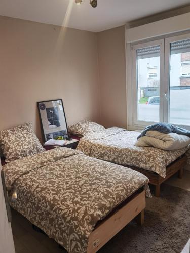 deux lits dans une chambre avec une fenêtre dans l'établissement Maison du bonheur, à Dunkerque