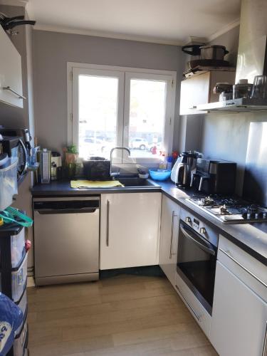 une cuisine avec des armoires blanches et un four à plaques de cuisson dans l'établissement Maison du bonheur, à Dunkerque