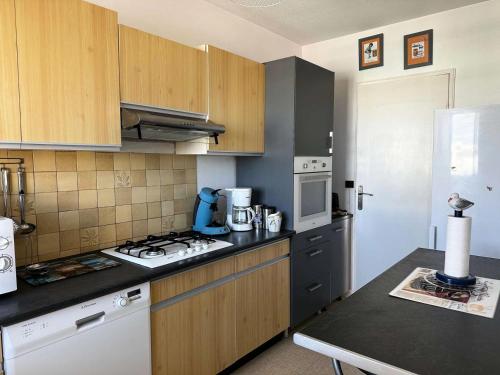 une cuisine avec des armoires en bois et un four à plaques de cuisson dans l'établissement Résidence Sun Beach - Appartement vue mer avec 2 balcons, proche plage MAE-9694, à Arcachon