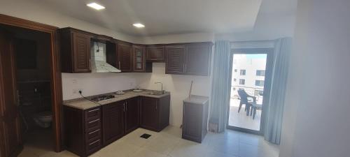 a kitchen with wooden cabinets and a sliding glass door at مراسيم للشقق الفندقية in Amman