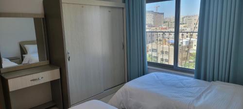 a bedroom with a bed and a large window at مراسيم للشقق الفندقية in Amman