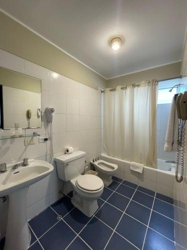 a bathroom with a toilet and a sink and a tub at Hotel Carrera in Lima