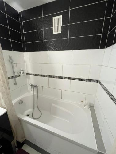 une baignoire blanche dans une salle de bain avec du carrelage noir et blanc dans l'établissement Le petit cocon, à Grenoble