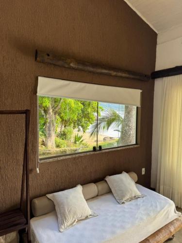 a bedroom with a large window above a bed at Casa da Ilha in Praia de Araçatiba