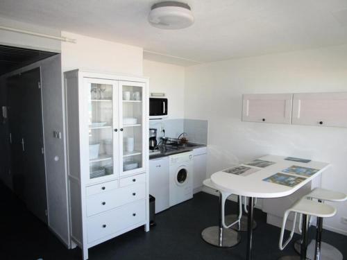 une cuisine avec une armoire blanche et une table dans l'établissement Résidence Ortal - Charmant appartement 4 personnes front de mer à Lacanau Océan MAE-0341, à Lacanau