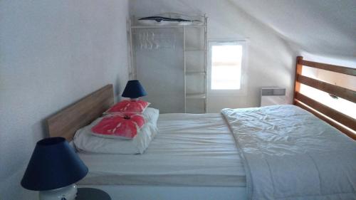 une chambre avec un lit avec deux oreillers rouges dans l'établissement Résidence Cigalines - Maisonnette mitoyenne 4 pers, résidence avec piscine, à Lacanau Océan MAE-0371, à Lacanau