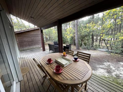 une table et des chaises en bois sur une terrasse dans l'établissement Résidence Vitanova - Maison spacieuse 8 personnes proche golf et pistes cyclables à Lacanau Océan MAE-0391, à Lacanau